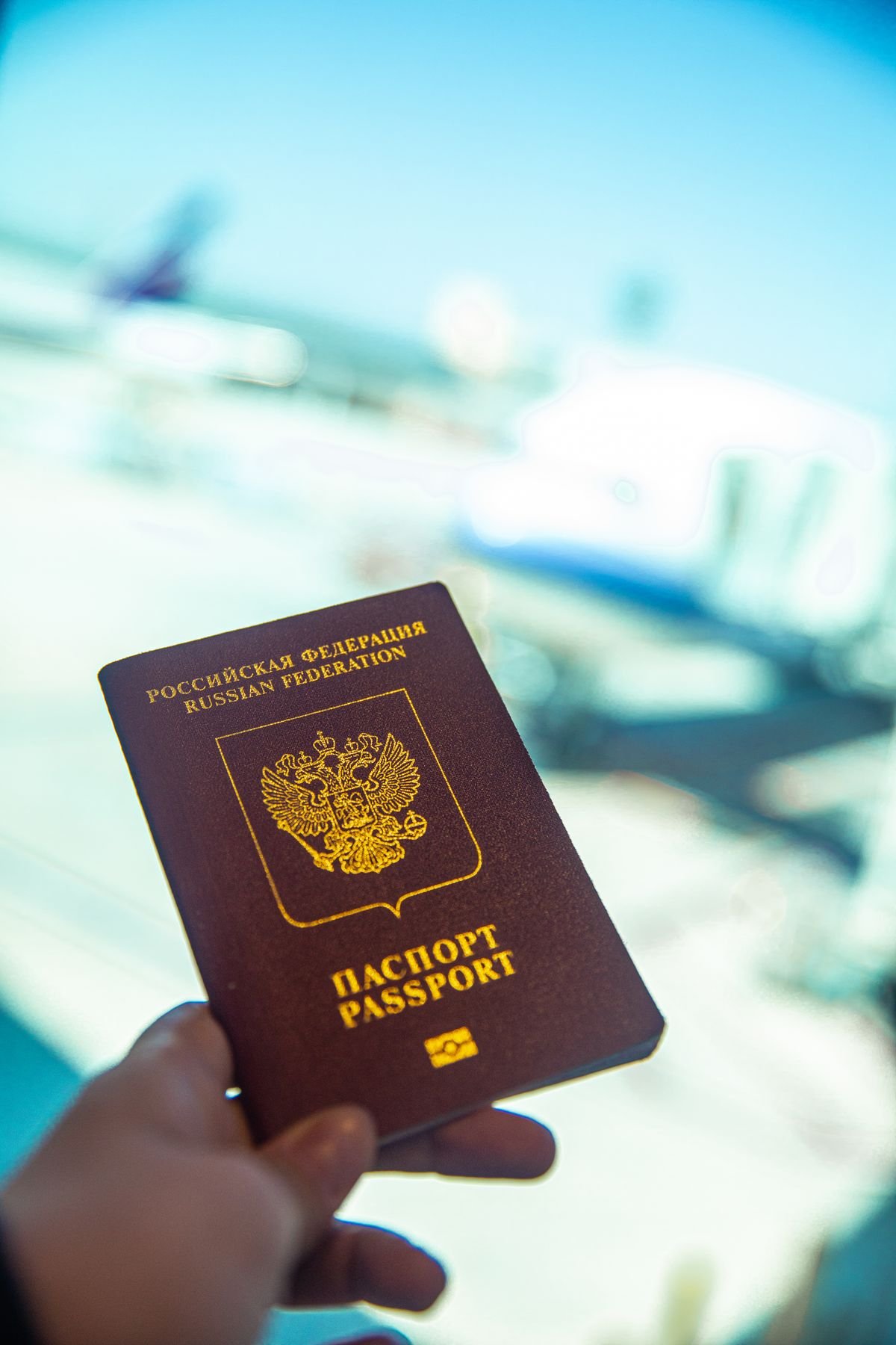 Person holding a passport near an airport gate window