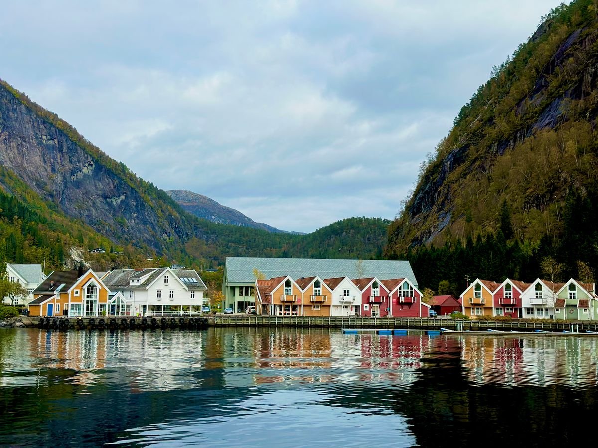 Colorful houses reflected in calm fjord waters with a mountain backdrop in Norway