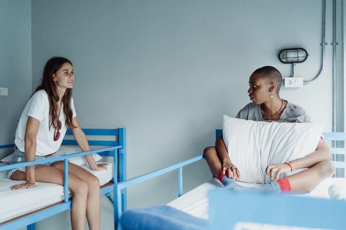 Two travelers sitting and talking casually on bunk beds in a hostel