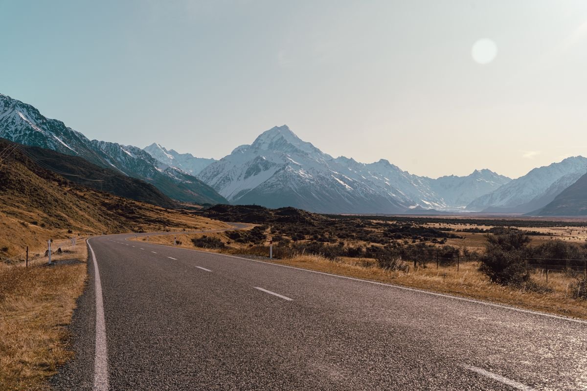Open road leading toward Aoraki Mount Cook framed by alpine mountains
