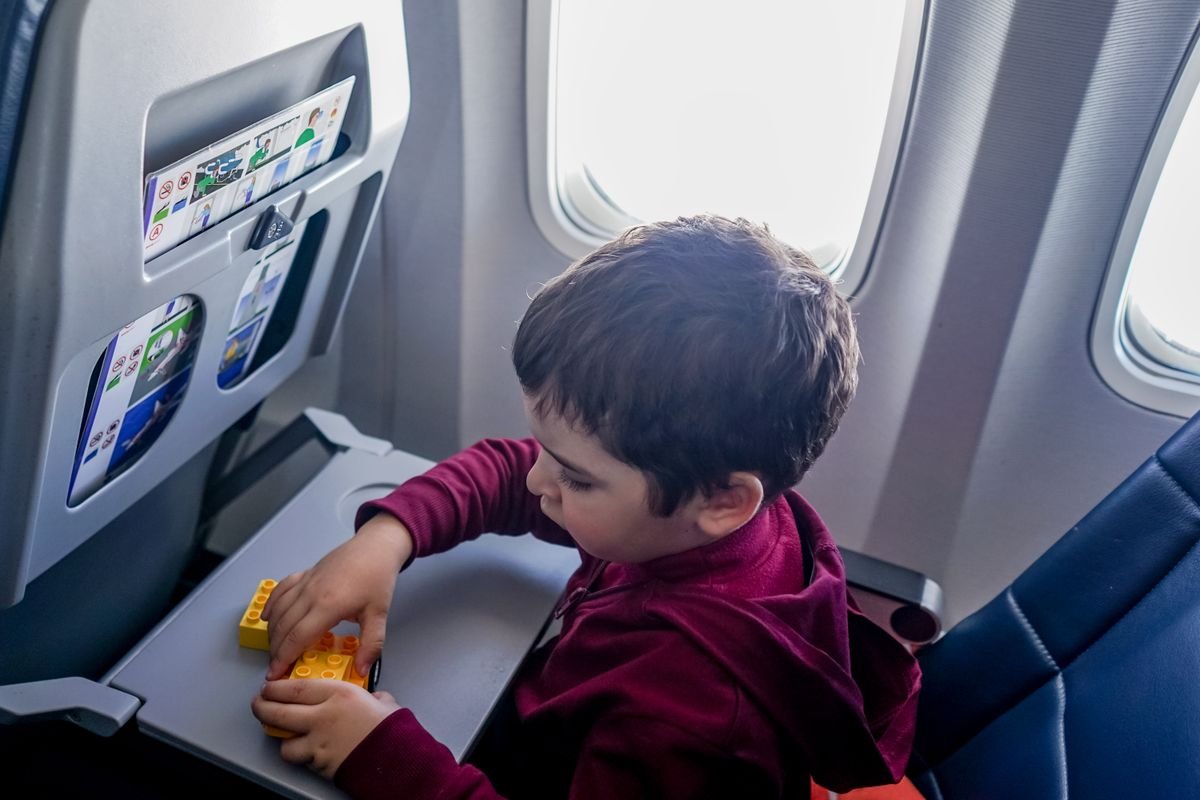 Young child playing with a small toy while seated on an airplane