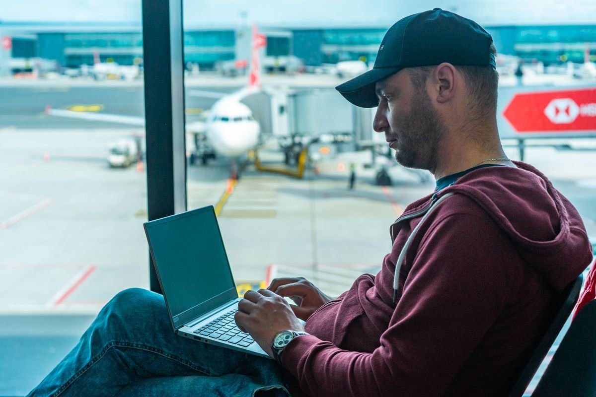 Traveler working on a laptop in an airport terminal near the gate
