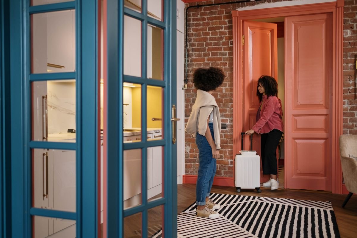 Two travelers with luggage in an apartment hallway getting ready to travel